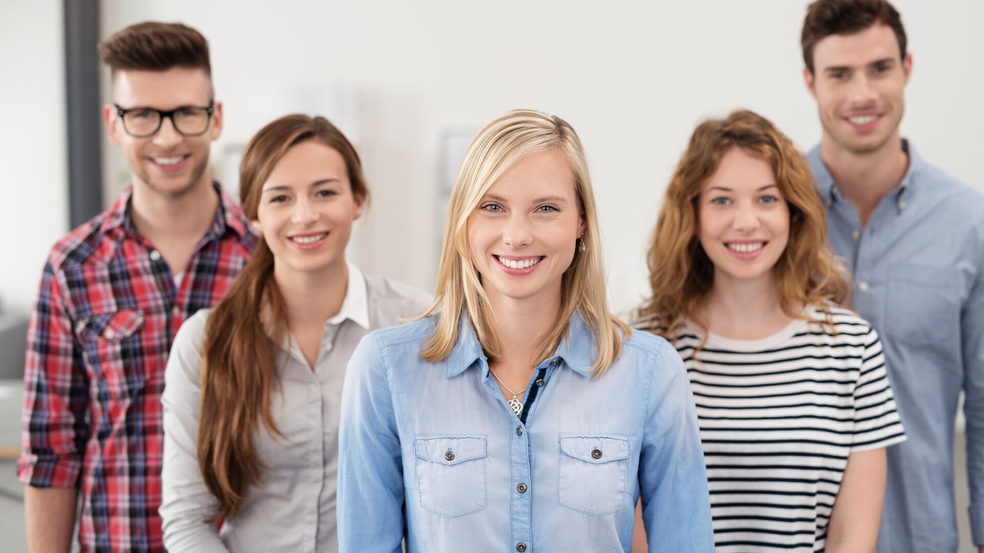 Eine Gruppe junger Menschen steht lächelnd zusammen und wirkt wie ein freundliches Team oder eine Lerngruppe.