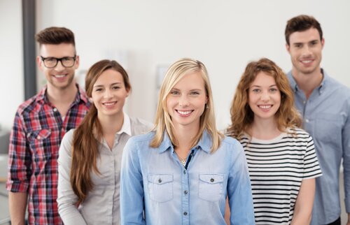 Gruppe junger Auszubildender lächelt in die Kamera – Symbolbild für die Prüfungsvorbereitung kaufmännischer Ausbildungsberufe an der IHK Akademie Ingolstadt.