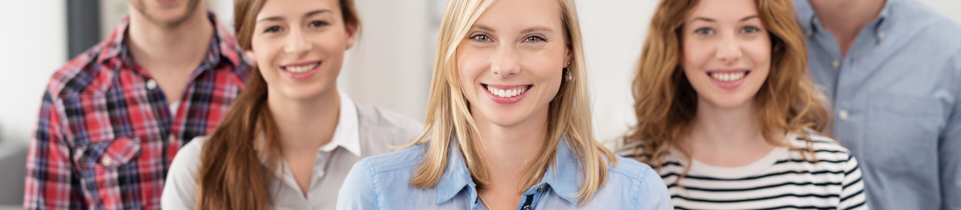 Eine Gruppe junger Menschen steht lächelnd zusammen und wirkt wie ein freundliches Team oder eine Lerngruppe.