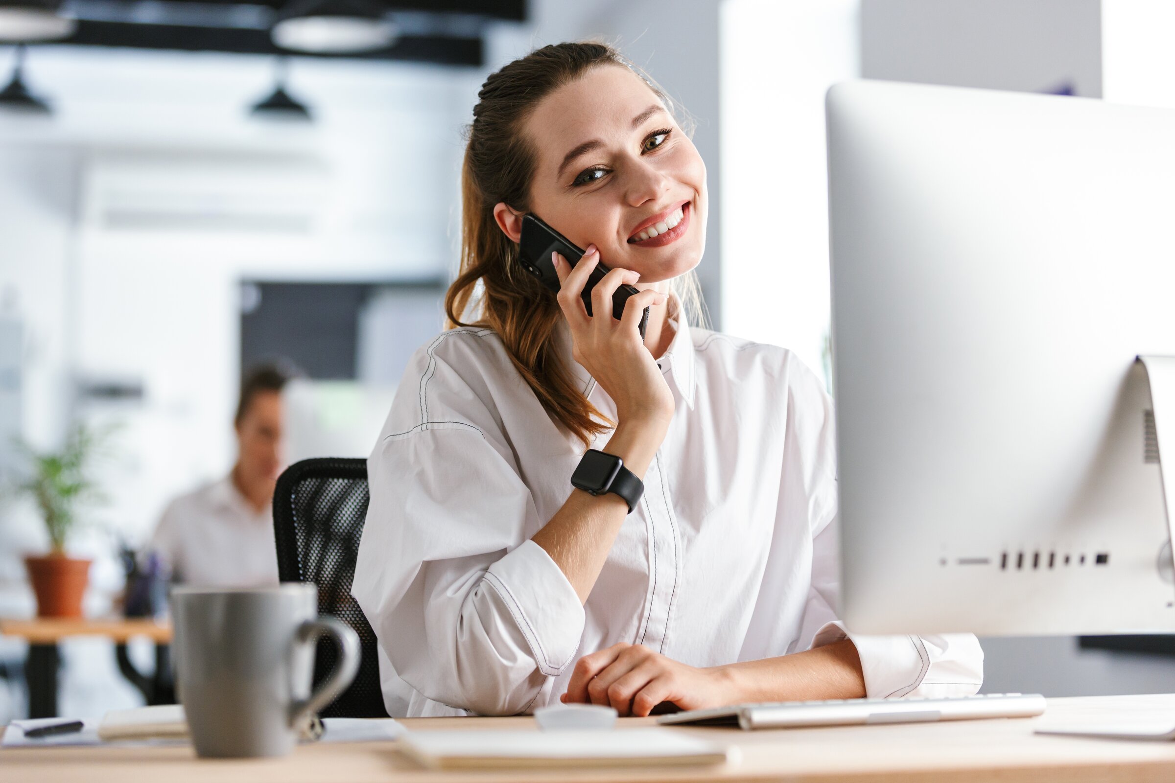 Junge Mitarbeiterin telefoniert am Schreibtisch und steht stellvertretend für die Generation Z im modernen Arbeitsumfeld.