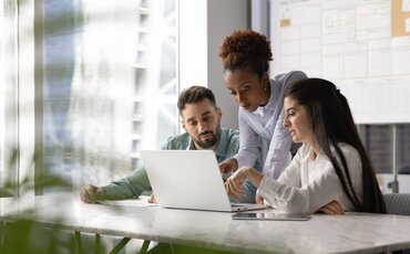 Drei Personen arbeiten gemeinsam am Laptop – Symbol für praxisorientierte Weiterbildung für Ausbilderinnen und Ausbilder.