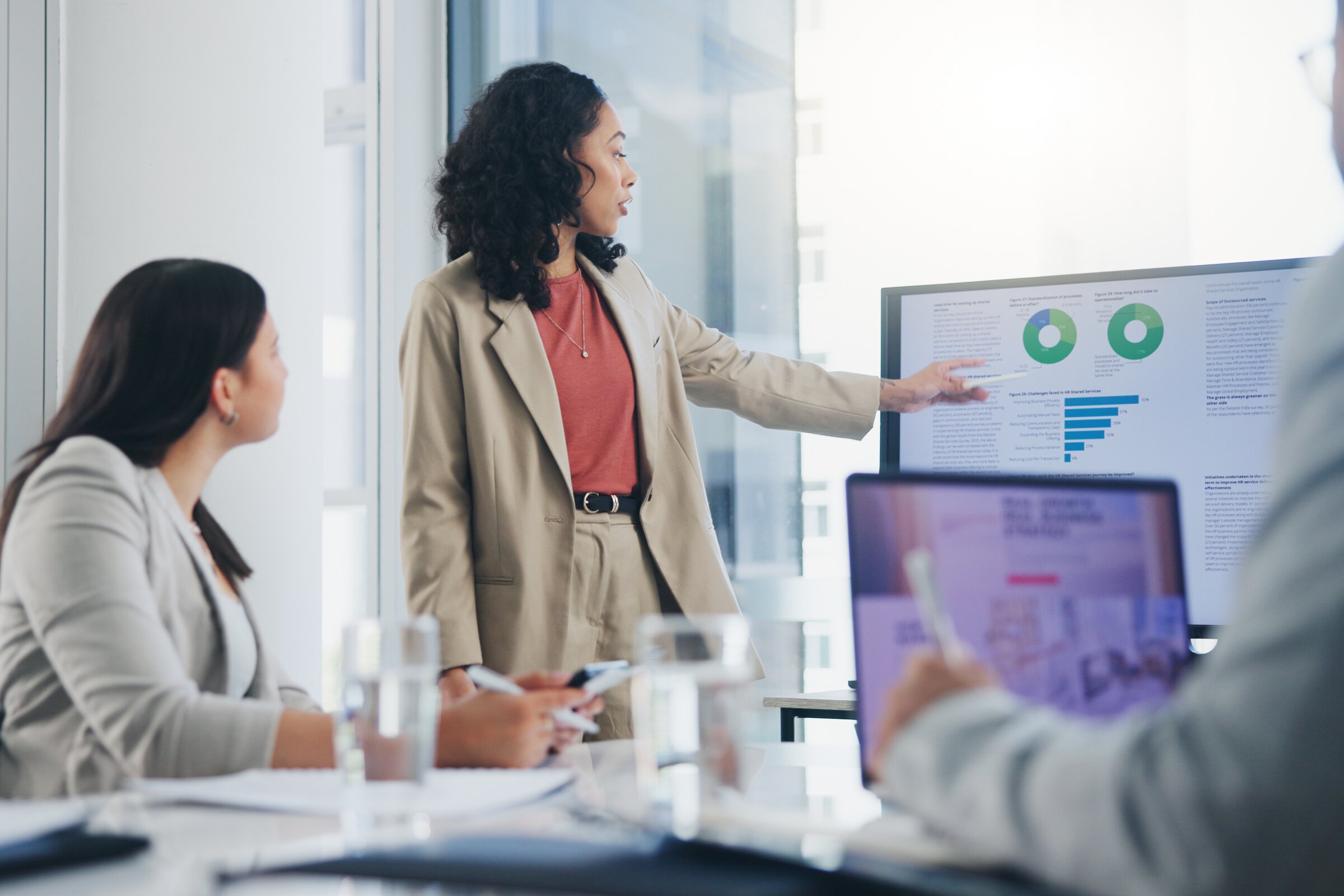 Eine vierköpfige Gruppe hält einen kreativen Workshop vor einer Glaswand voller bunter Haftnotizen.