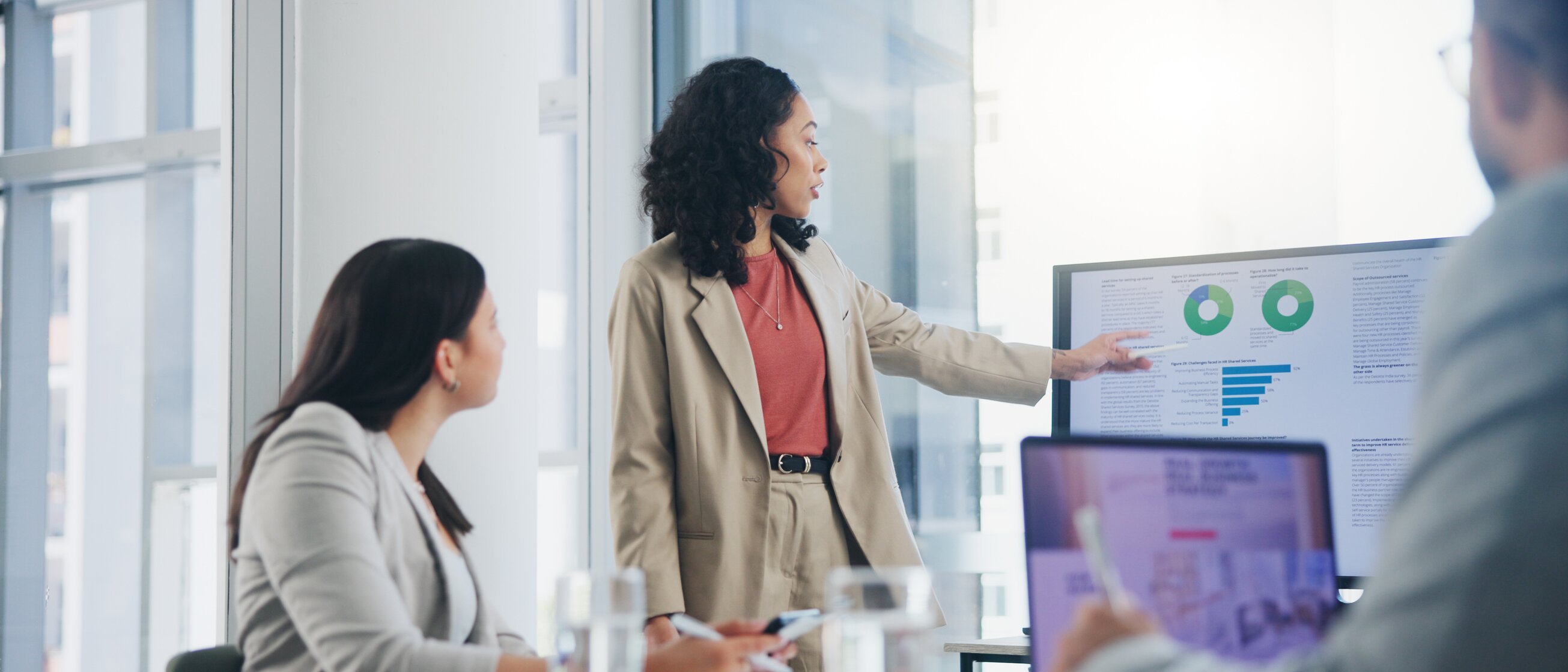 Eine Frau präsentiert Geschäftszahlen und Diagramme in einem Meeting – Symbol für praxisnahe IHK-Weiterbildungen im Controlling zur fundierten Analyse und Steuerung betriebswirtschaftlicher Prozesse.