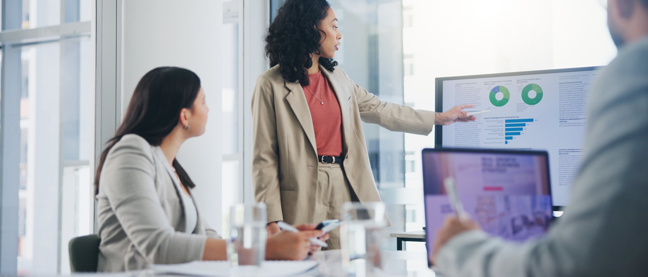 Eine Frau präsentiert Geschäftszahlen und Diagramme in einem Meeting – Symbol für praxisnahe IHK-Weiterbildungen im Controlling zur fundierten Analyse und Steuerung betriebswirtschaftlicher Prozesse.