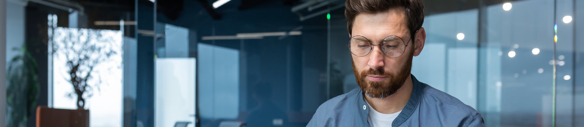 Ein Mann arbeitet konzentriert an seinem Schreibtisch, nutzt Laptop, Notizen und Taschenrechner für seine Aufgaben.