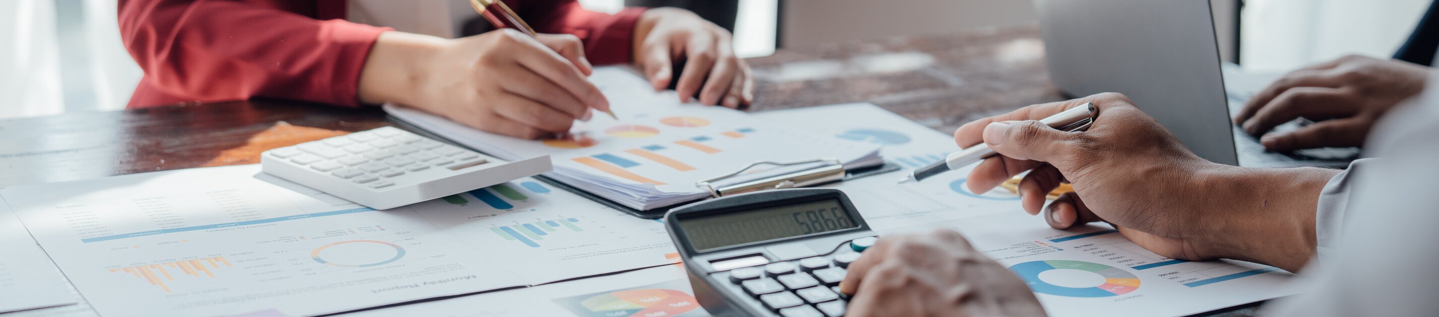 Das Bild zeigt mehrere Personen, die gemeinsam Finanz- und Diagrammdaten besprechen und auswerten.