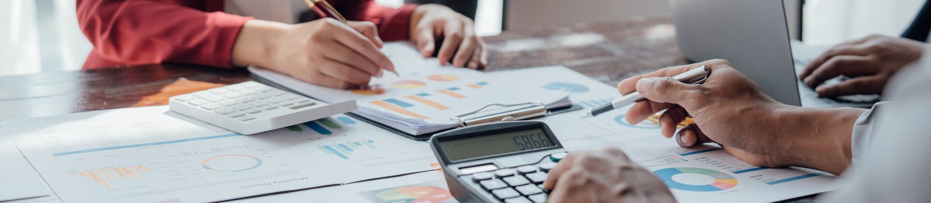 Das Bild zeigt mehrere Personen, die gemeinsam Finanz- und Diagrammdaten besprechen und auswerten.