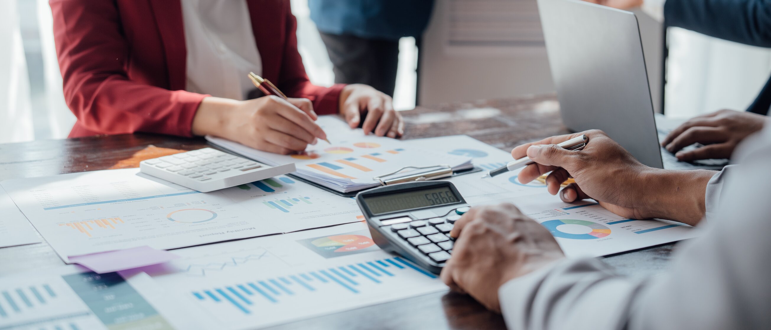 Das Bild zeigt mehrere Personen, die gemeinsam Finanz- und Diagrammdaten besprechen und auswerten.