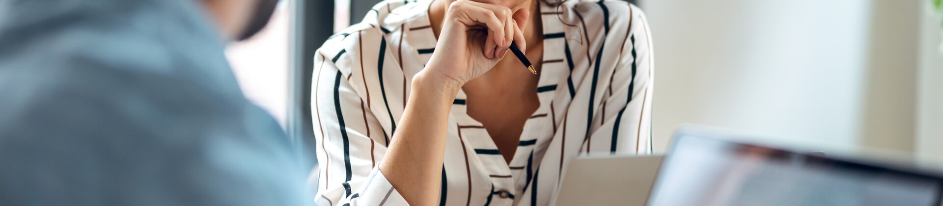 Eine Frau führt ein freundliches Gespräch mit einer anderen Person in einem Büro.