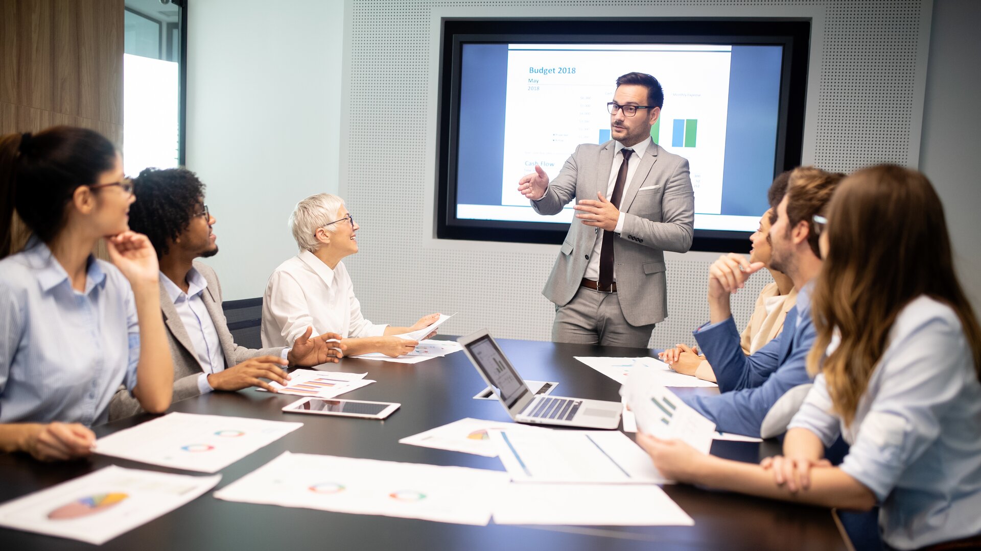 Eine Gruppe von Mitarbeitenden sitzt im Konferenzraum und hört einer Präsentation zu.