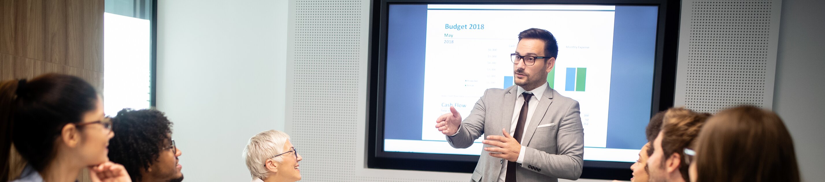 Eine Gruppe von Mitarbeitenden sitzt im Konferenzraum und hört einer Präsentation zu.