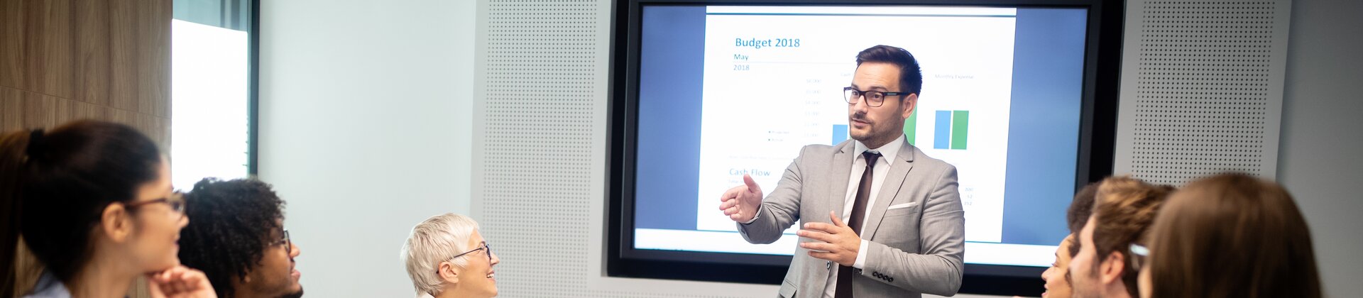 Eine Gruppe von Mitarbeitenden sitzt im Konferenzraum und hört einer Präsentation zu.