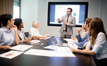 Ein Dozent präsentiert Finanzdaten vor einem Team – Weiterbildung im Controlling für fundierte Unternehmenssteuerung.