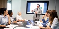 Eine Gruppe von Mitarbeitenden sitzt im Konferenzraum und hört einer Präsentation zu.