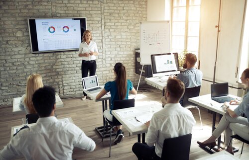 Trainerin präsentiert Fachinhalte auf einem Bildschirm – Weiterbildung mit praxisorientiertem Wissenstransfer in den Zertifikatslehrgängen der IHK Akademie München und Oberbayern.