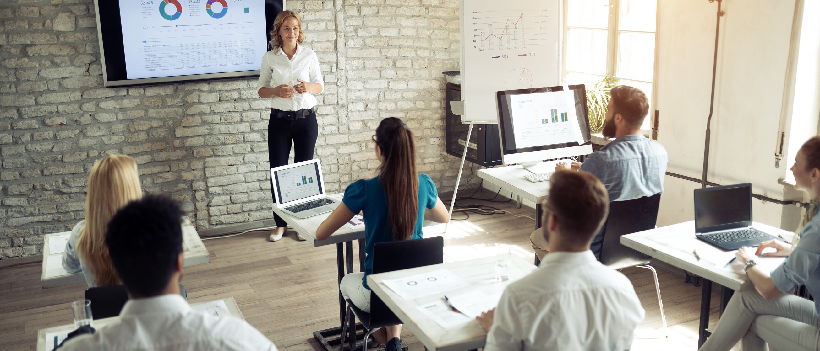 Dozentin erklärt Präsentation vor einer Gruppe von Teilnehmenden – Weiterbildung zum geprüften Immobiliardarlehensvermittler oder zur geprüften Immobiliardarlehensvermittlerin (IHK) gemäß § 34i GewO für rechtssichere Beratung in der Immobilienfinanzierung.