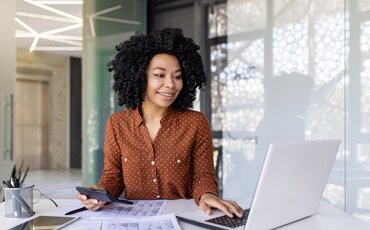 Eine Frau analysiert Finanzdaten am Laptop – Weiterbildung im Bereich Finanzanlagen und Versicherungen für mehr Sicherheit bei Investmententscheidungen.