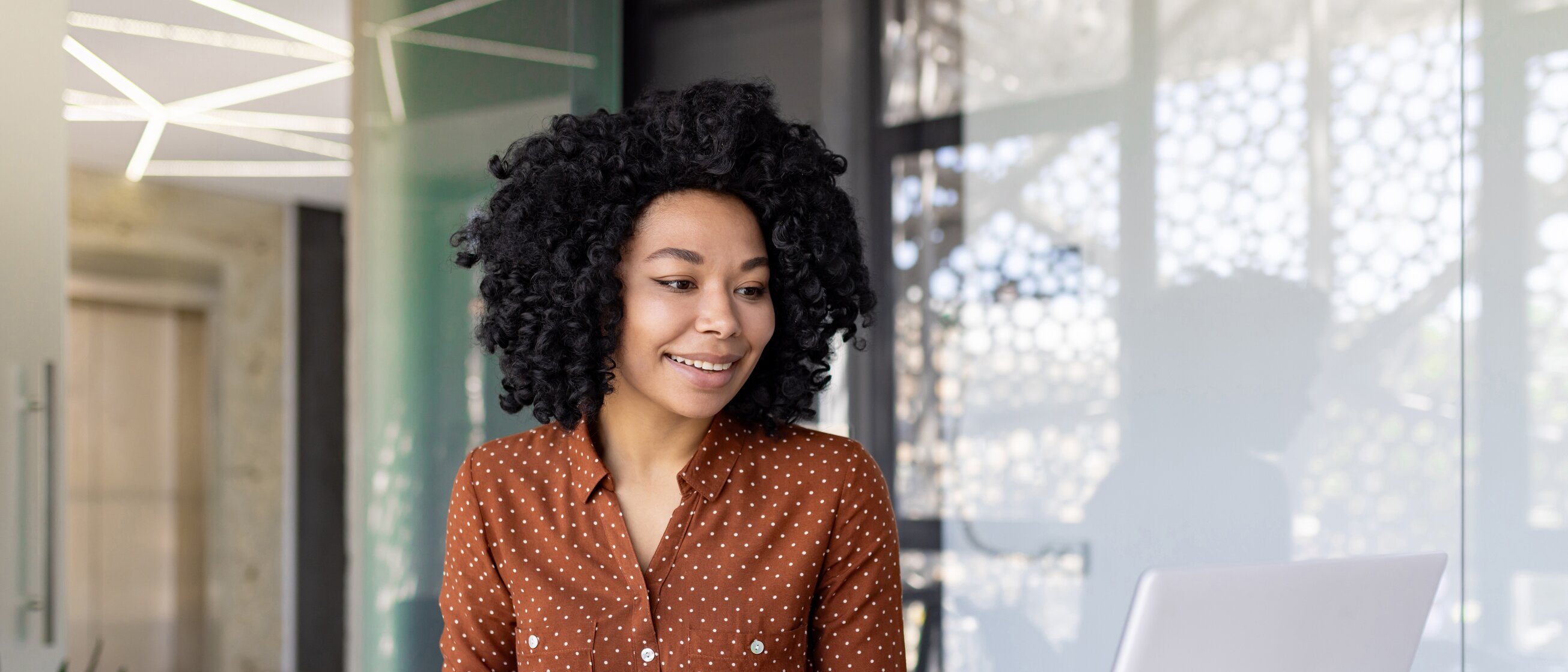 Das Bild zeigt eine Person, die konzentriert am Schreibtisch arbeitet und dabei sowohl einen Laptop als auch einen Taschenrechner benutzt.
