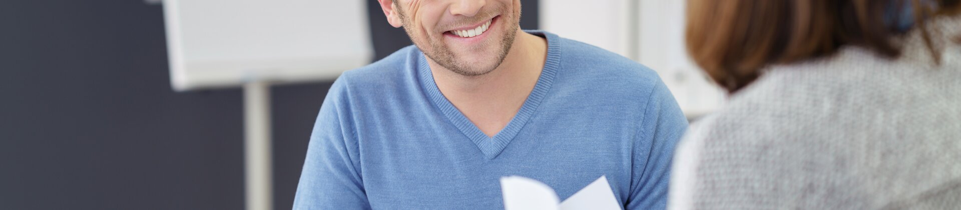 Ein Mann führt ein freundliches Gespräch, während er gemeinsam mit einer anderen Person Dokumente durchgeht.