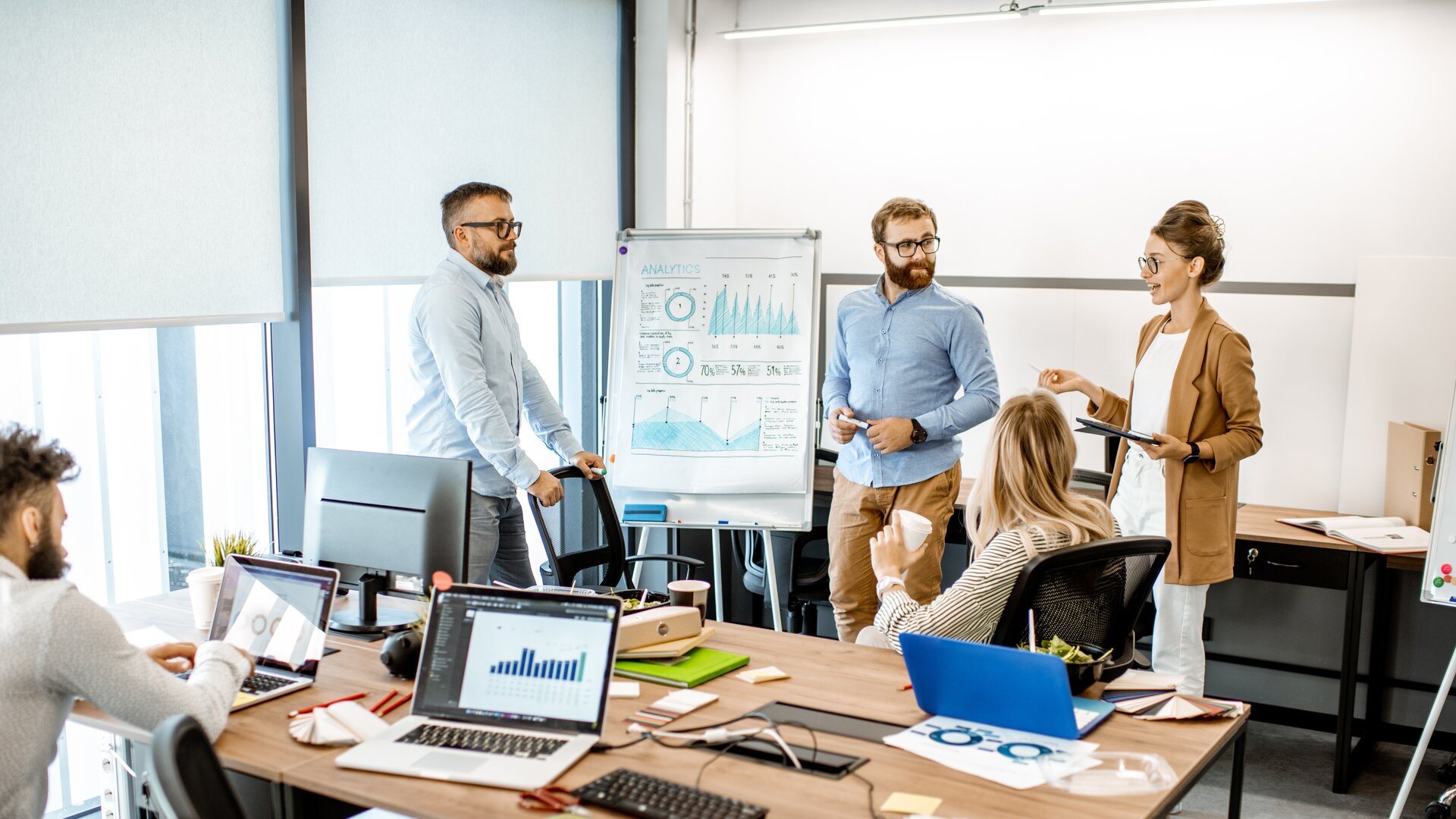 Eine kleine Gruppe arbeitet im modernen Büro gemeinsam an einer Präsentation und bespricht Analyseergebnisse.