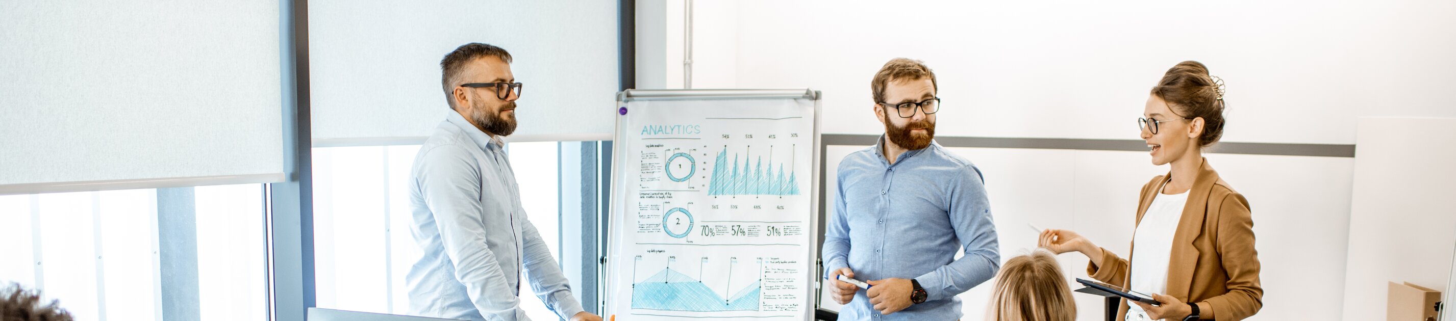 Eine kleine Gruppe arbeitet im modernen Büro gemeinsam an einer Präsentation und bespricht Analyseergebnisse.