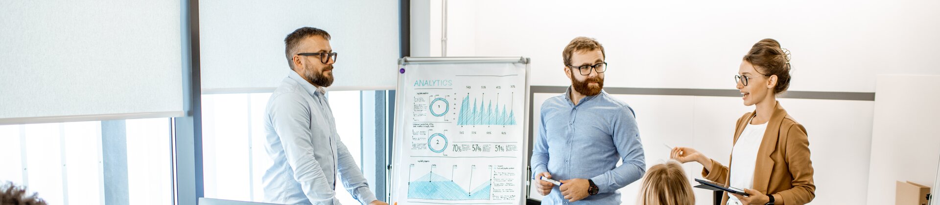 Eine kleine Gruppe arbeitet im modernen Büro gemeinsam an einer Präsentation und bespricht Analyseergebnisse.