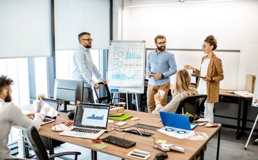 Team präsentiert Finanzdiagramme in einem modernen Büro – praxisnahe Weiterbildung im Bereich Bilanzierung, Aufbau und Analyse von Jahresabschlüssen.