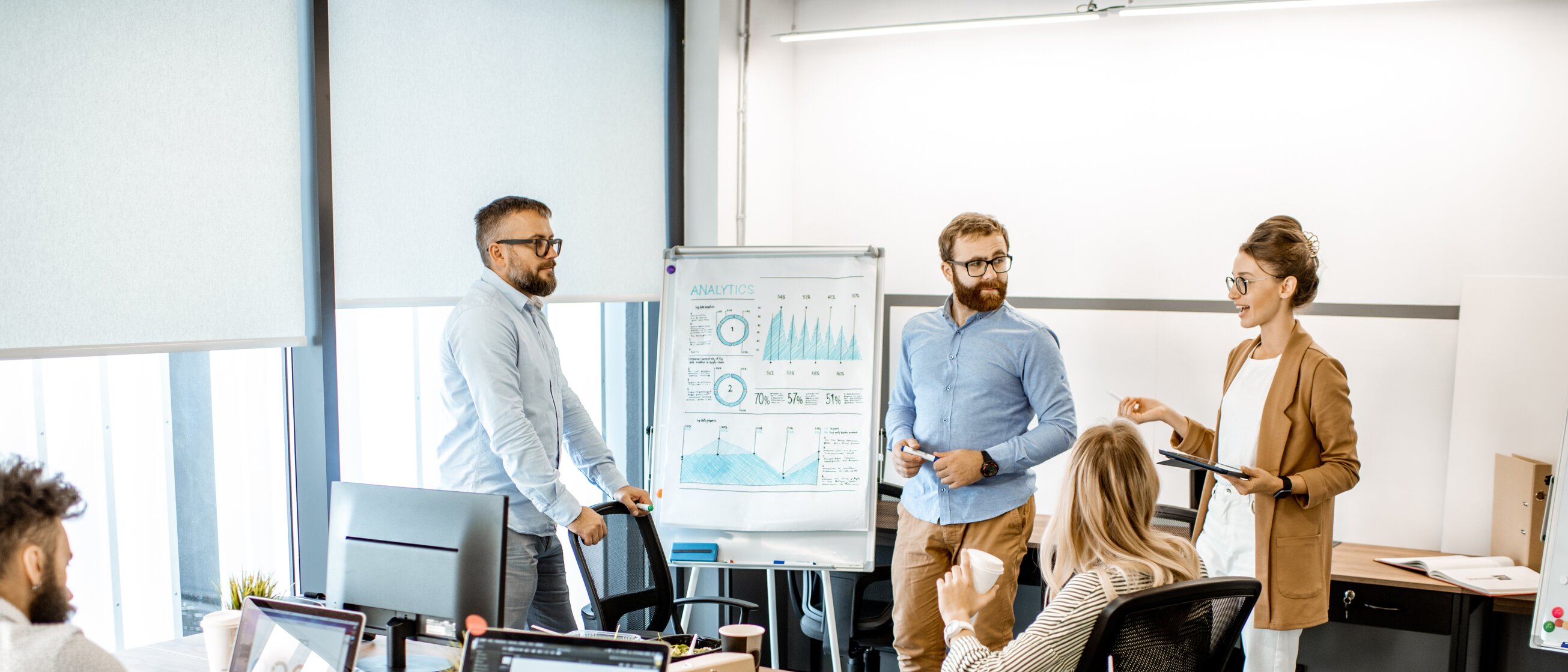 Eine kleine Gruppe arbeitet im modernen Büro gemeinsam an einer Präsentation und bespricht Analyseergebnisse.
