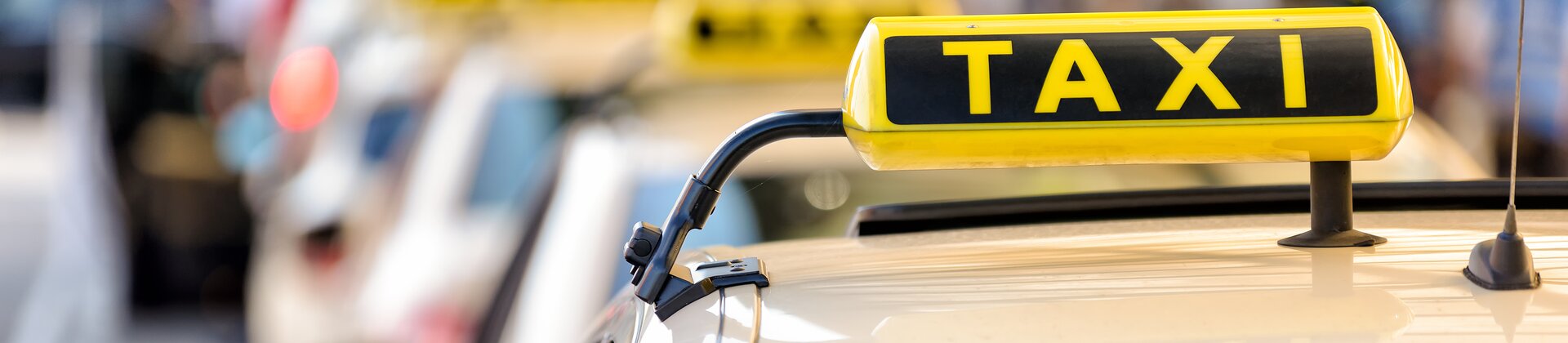 Eine Reihe von Taxis steht wartend hintereinander auf einer Straße