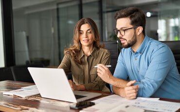 Zwei Personen besprechen Unterlagen am Laptop in modernem Büro – Symbolbild für kaufmännische Weiterbildungen in Traunstein