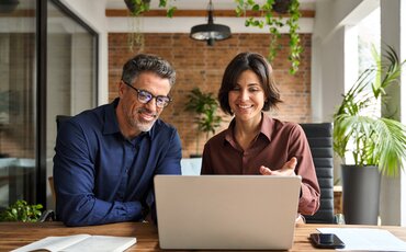 Zwei Personen arbeiten gemeinsam am Laptop in einem modernen Büro – Symbol für Teamarbeit, strategisches Denken und betriebswirtschaftliche Weiterbildung.