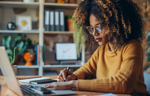 Trainerin arbeitet am Laptop und füllt Unterlagen am Schreibtisch aus