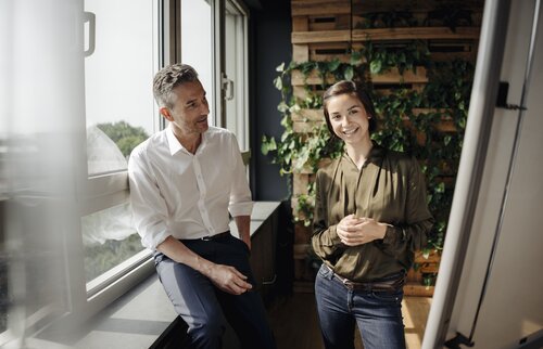 Zwei Mitarbeitende im Gespräch in freundlicher Atmosphäre – symbolisiert den gesellschaftlichen Bildungsauftrag und das wertschätzende Miteinander an der IHK Akademie München und Oberbayern.