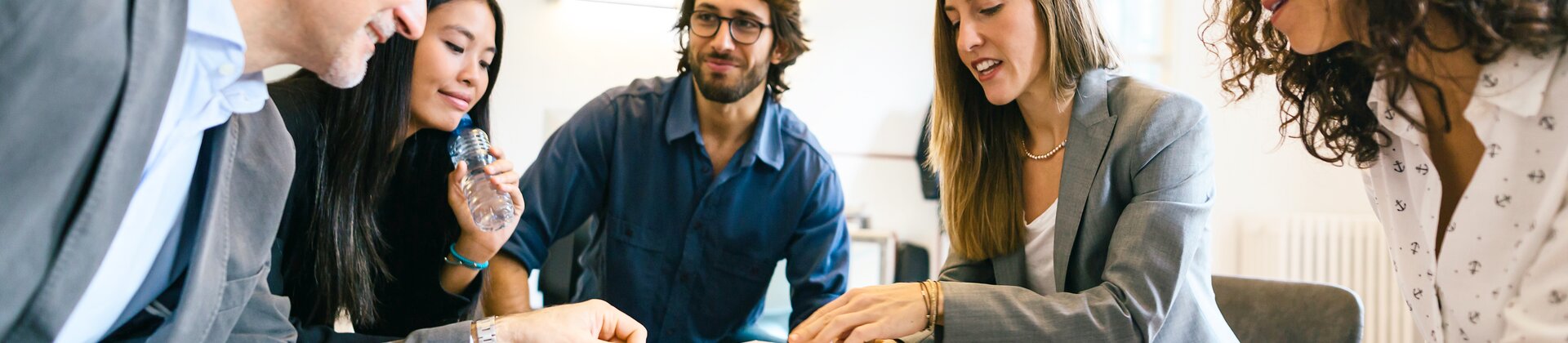 Eine Gruppe von fünf Personen sitzt in einem Kreis und arbeitet konzentriert gemeinsam an Unterlagen.