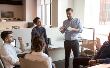 Eine Person moderiert eine Gruppe in einem modernen Konferenzraum – Symbol für Mediation, Konfliktlösung und konstruktive Kommunikation in Unternehmen.