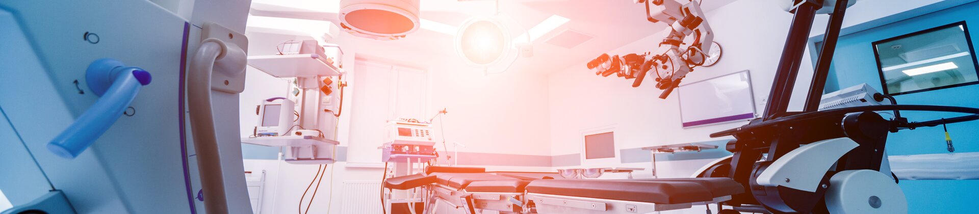 Ein hochmodern ausgestatteter Operationssaal mit robotergestützter Medizintechnik und bildgebenden Geräten.