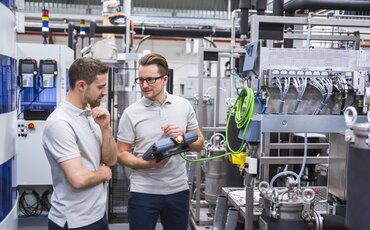 Zwei Männer besprechen Messdaten in einer modernen Werkhalle – Symbolbild für technische Weiterbildungen an der IHK Akademie Mühldorf