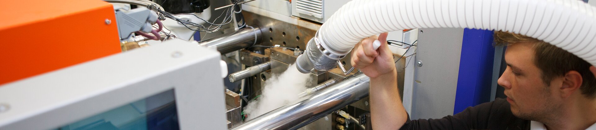 Zwei Personen überprüfen gemeinsam eine Maschine, während ein Kühl- oder Dampfprozess sichtbar aktiv ist.