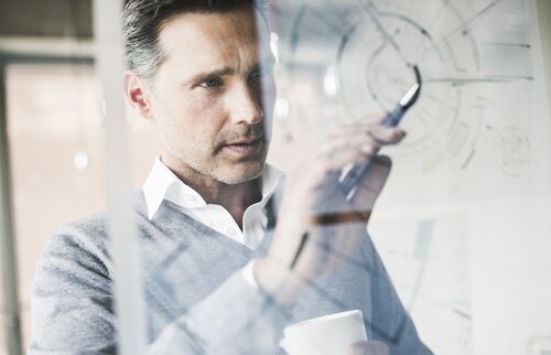 Ein Technischer Betriebswirt arbeitet konzentriert an einem Schaubild auf Glas – Sinnbild für technisches Know-how, Analysefähigkeit und praxisorientiertes Management.