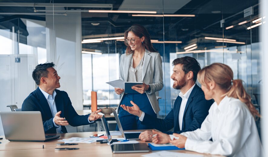 Ein gut gelauntes Team bespricht gemeinsam neue Ideen, während eine Kollegin ihre Unterlagen präsentiert.