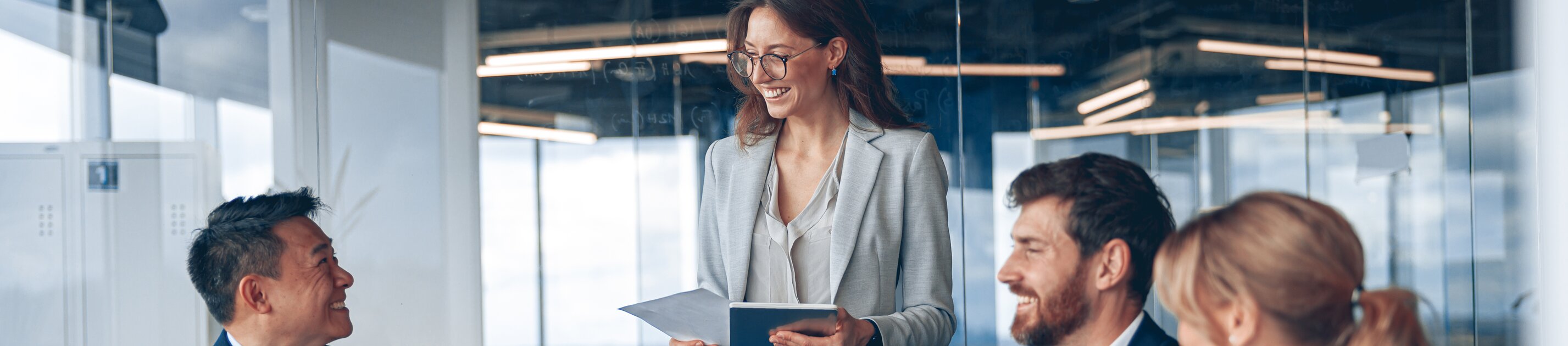 Ein gut gelauntes Team bespricht gemeinsam neue Ideen, während eine Kollegin ihre Unterlagen präsentiert.