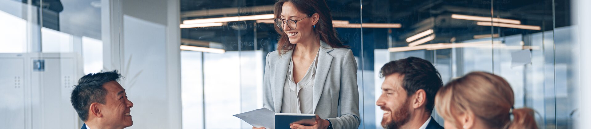 Ein gut gelauntes Team bespricht gemeinsam neue Ideen, während eine Kollegin ihre Unterlagen präsentiert.