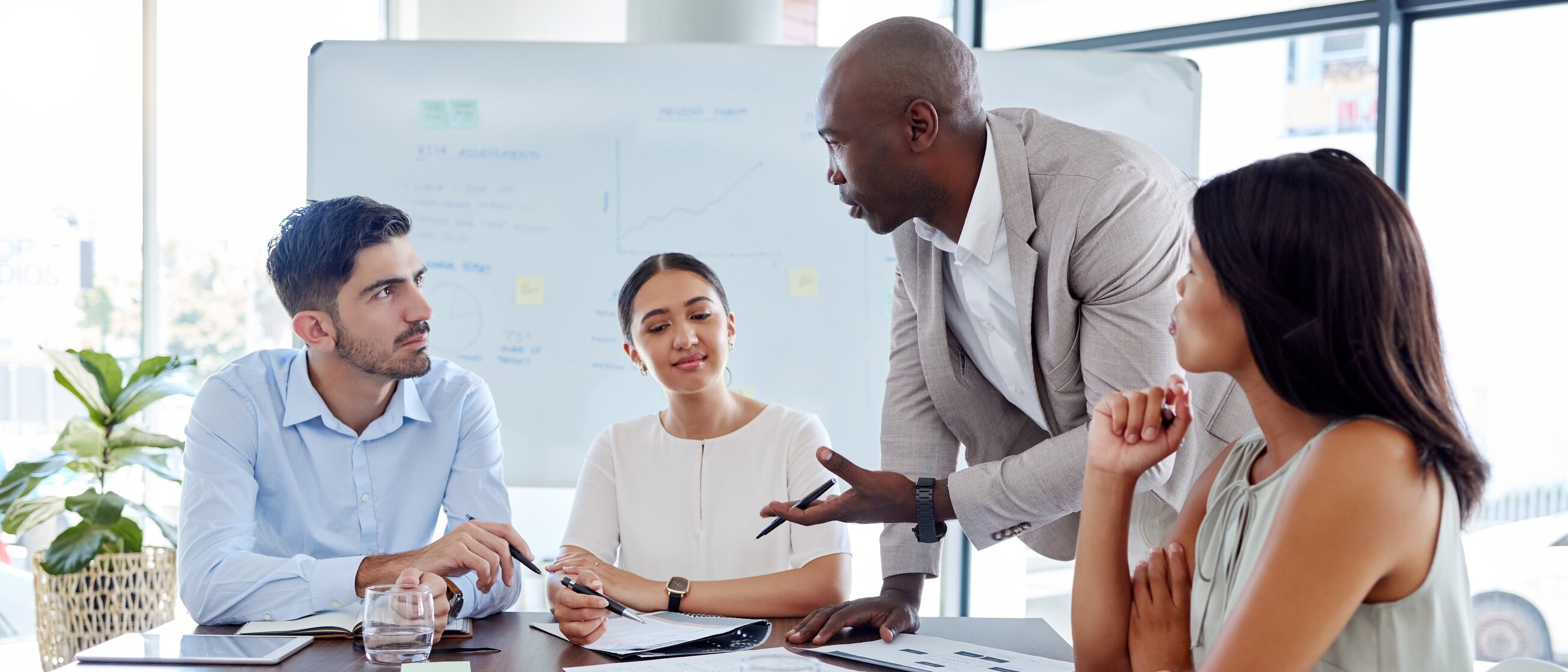 Eine Gruppe von vier Personen sitzt in einem Tisch n einem modernen Seminarraum und führt ein Gespräch – Symbol für professionelles Coaching, persönliche Weiterentwicklung und vertrauensvollen Austausch.