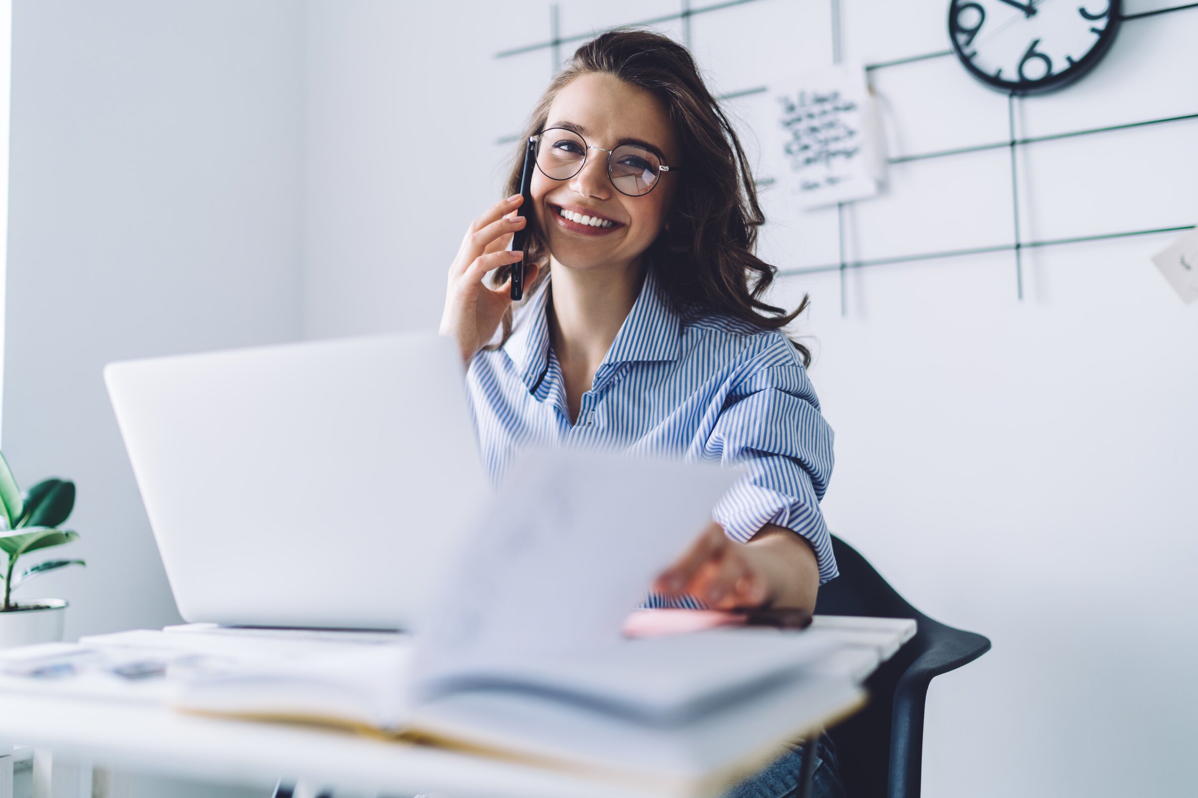 Junge Frau telefoniert im Büro und arbeitet an Unterlagen – Symbol für Organisationstalent, Verantwortung und Karrierechancen in der Veranstaltungstechnik.