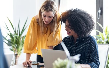 Zwei Frauen arbeiten gemeinsam am Laptop in heller Umgebung – Symbolbild für Seminare in Traunstein