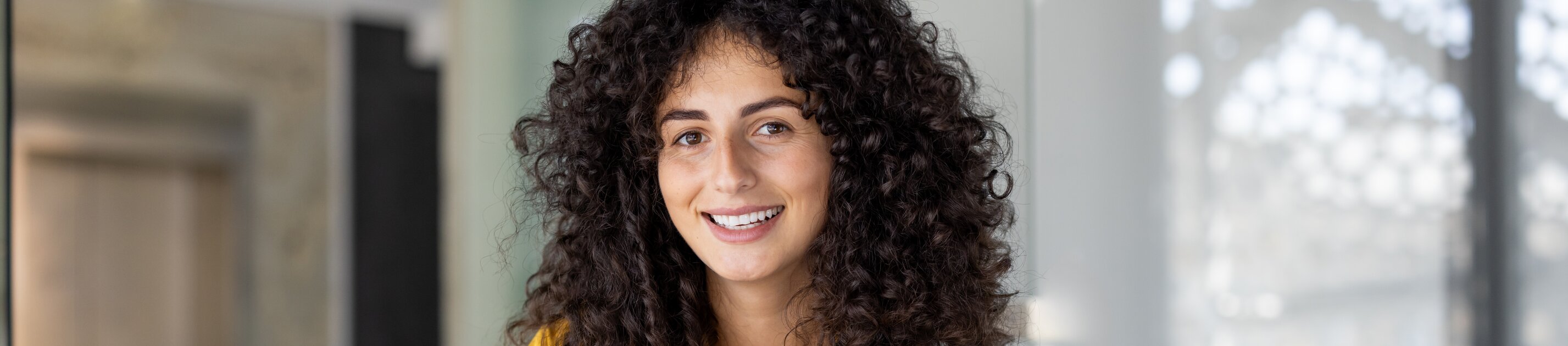 Eine junge Frau arbeitet lächelnd im Büro und wirkt konzentriert bei der Bearbeitung ihrer Unterlagen.