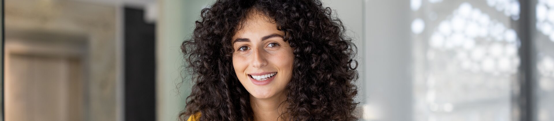 Eine junge Frau arbeitet lächelnd im Büro und wirkt konzentriert bei der Bearbeitung ihrer Unterlagen.