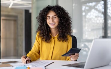 Junge Frau arbeitet konzentriert mit Taschenrechner und Unterlagen – Weiterbildung zur IHK-Fachkraft Rechnungswesen