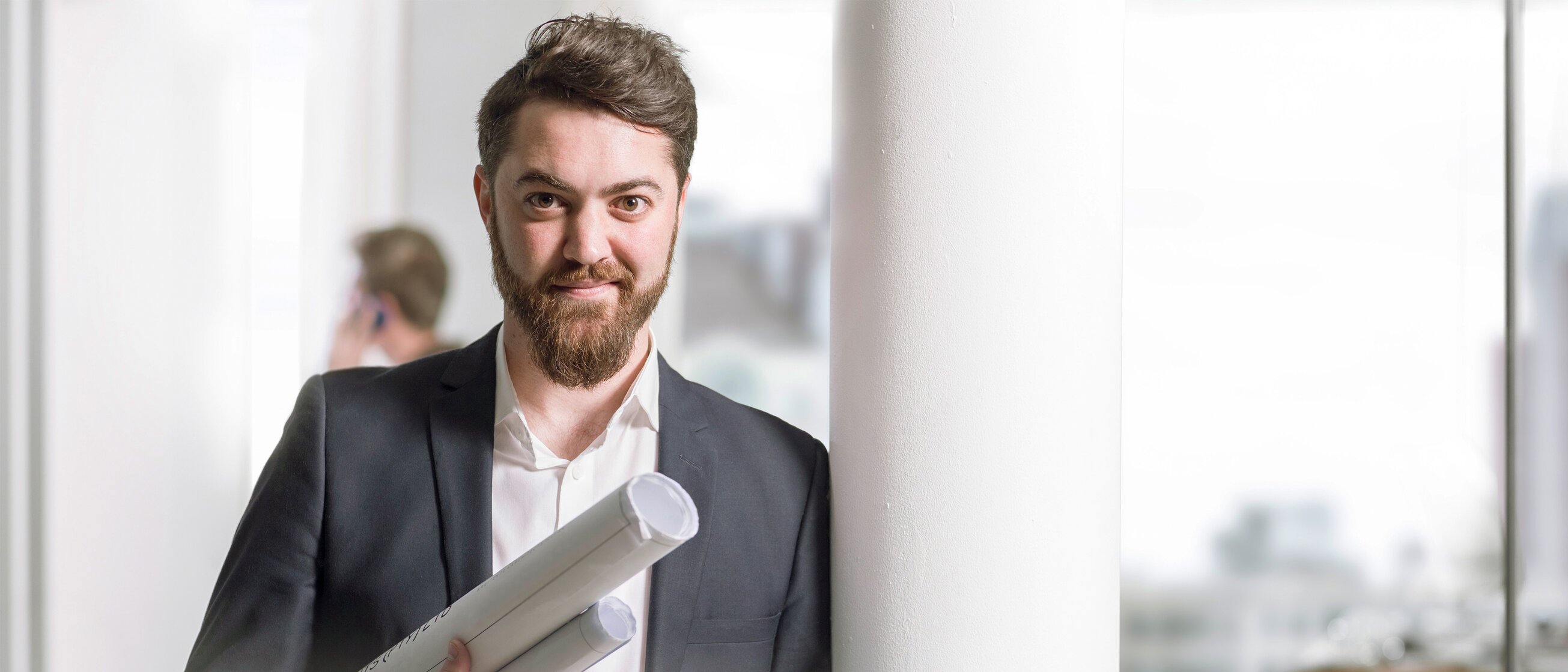 Weiterbildung für Bauträger: Ein Bauträger hält Baupläne in der Hand.