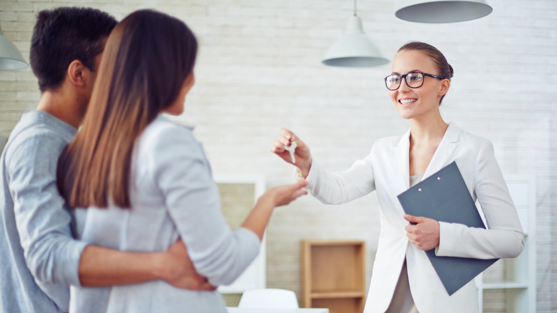 Maklerin übergibt einem Paar den Schlüssel zu einer Immobilie